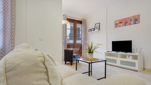 A living room with a sofa, a TV on a stand, a small table with a plant, and a door leading outside. - Holiday Apartment 'Rolycar 102' with Wi-Fi (Icod de los Vinos)