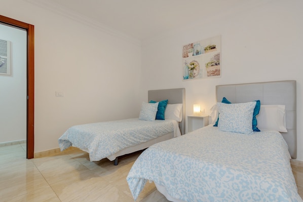A hotel room with two beds, a wooden door, and a wall with framed pictures.