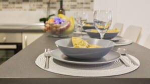 Ein Esstisch mit einer Schüssel Essen, einem Weinglas und Besteck.