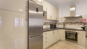 Eine moderne Küche mit Edelstahlgeräten, beigen Schränken und einer gefliesten Spritzschutzwand.