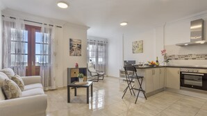 Un salon moderne avec un canapé, une table à manger et des chaises. Il y a une cuisine équipée d’une cuisinière et de placards.