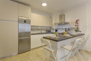 A modern kitchen with a stainless steel refrigerator, white cabinets, a microwave, and a small island with chairs. - Holiday Apartment 'Rolycar 203' with Wi-Fi (Icod de los Vinos)