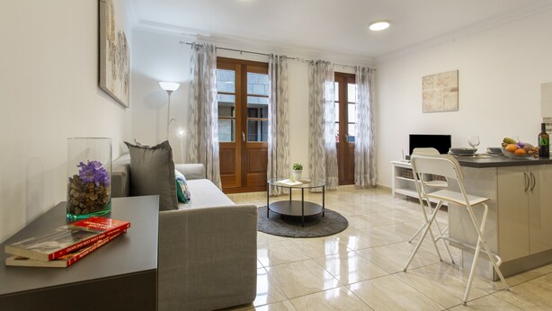 A modern living room with a sofa, a coffee table, and a dining area with a chair and a small table. - Holiday Apartment 'Rolycar 204' with Wi-Fi (Icod de los Vinos)