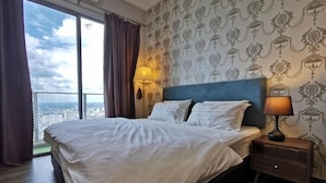 A hotel room with a large bed, a nightstand with a lamp, and a view of the city through large windows. - Mykey Silverscape B-39-07 Melaka City (Melaka)