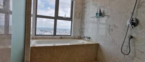 A bathroom with a bathtub, a window, and a shower.