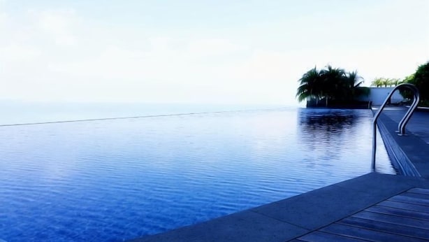 An infinity pool with a wooden deck and a view of the ocean. - Mykey Silverscape B-39-07 Melaka City (Melaka)