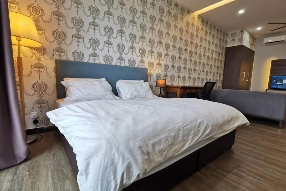 A hotel room with a large bed, a desk, a chair, and a TV.