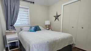 A bedroom with a bed, a nightstand, a lamp, a star decoration, and a wardrobe.