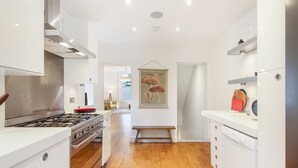 Una cocina moderna con armarios blancos, estufa de acero inoxidable y piso de madera.