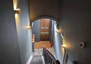 Una escalera que lleva a una puerta de madera con un felpudo en la base.