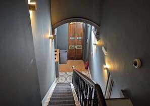 A staircase leading to a room with a wooden door, a trash bin, and a fire extinguisher. - Pass the Keys | Cosy King room in Central Bath (Bath)