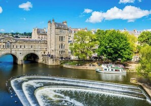 A historic building with a stone facade, a bridge, and a water feature with a boat. - Pass the Keys | Cosy King room in Central Bath (Bath)