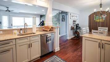 A modern kitchen with a central island, a coffee station, and a dining area with a wooden table and chairs.