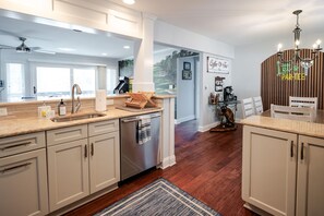 Een moderne keuken met een centraal eiland, een koffiehoek en een eethoek met een houten tafel en stoelen.