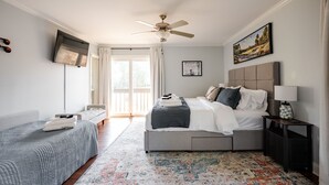 Une chambre à coucher avec un lit, une table de chevet, un ventilateur de plafond et une fenêtre.