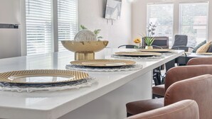 Una cocina moderna con encimera blanca, un tazón decorativo dorado y individuales tejidos.