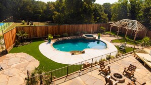 A backyard with a swimming pool, stone patio, wooden deck, and a wooden fence. - Bison Suite - relax in your private hot tub and explore the Ranch!  (Valley View)