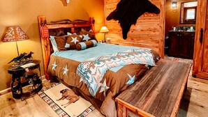 A rustic bedroom with a wooden bed, a mounted animal head, and a wooden bench. - Bison Suite - relax in your private hot tub and explore the Ranch!  (Valley View)