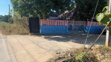 A gated property with a dirt road leading to a blue garage.
