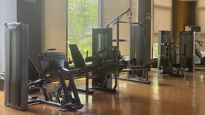 A gym with various exercise machines, large windows, and a polished wooden floor. - Levi & Moon Relax and Chill (Pasay City)