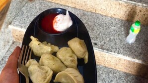 Un plato de dumplings con crema agria y salsa roja, sobre una escalera de granito.