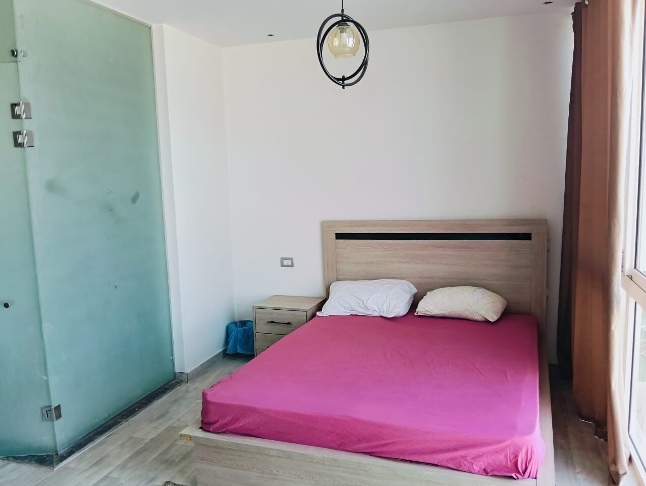 Une chambre à coucher avec un lit, une table de chevet, une lampe et une porte.