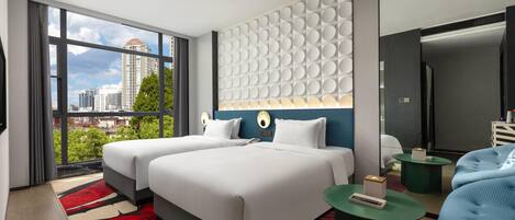 A modern hotel room with two beds, a large window offering a city view, a unique wall design, and a small seating area.