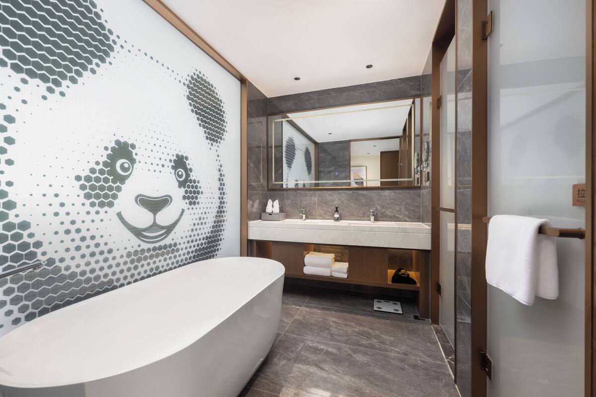 Ein modernes Badezimmer mit einer großen Badewanne, einem Waschtisch mit Spiegel und Fliesenboden.