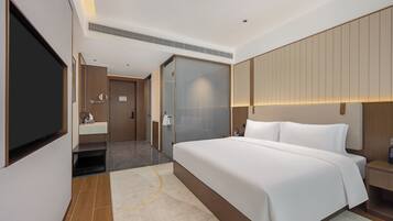 A modern hotel room with a large bed, a flat-screen TV, a bathroom with a mirror and sink, and a sliding door closet.