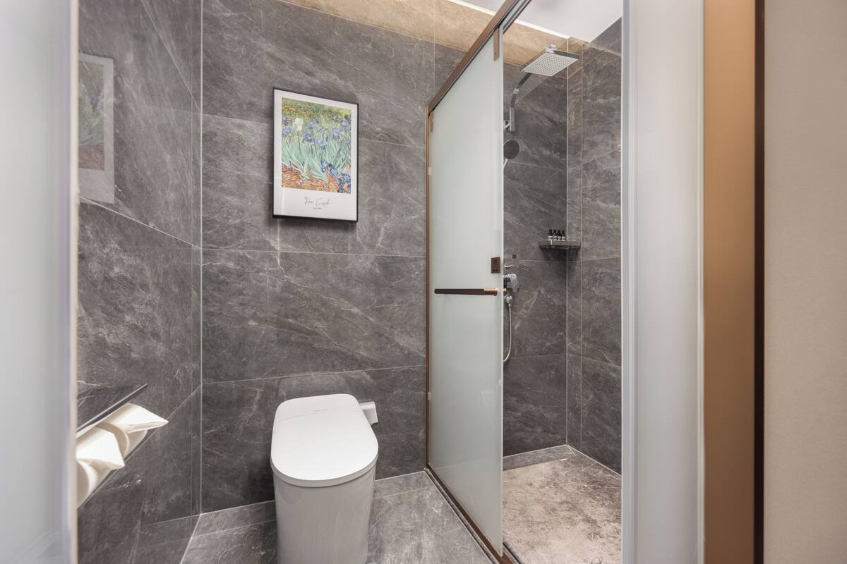 Ein modernes Badezimmer mit Duschkabine aus Glas, Toilette und Marmorwand.