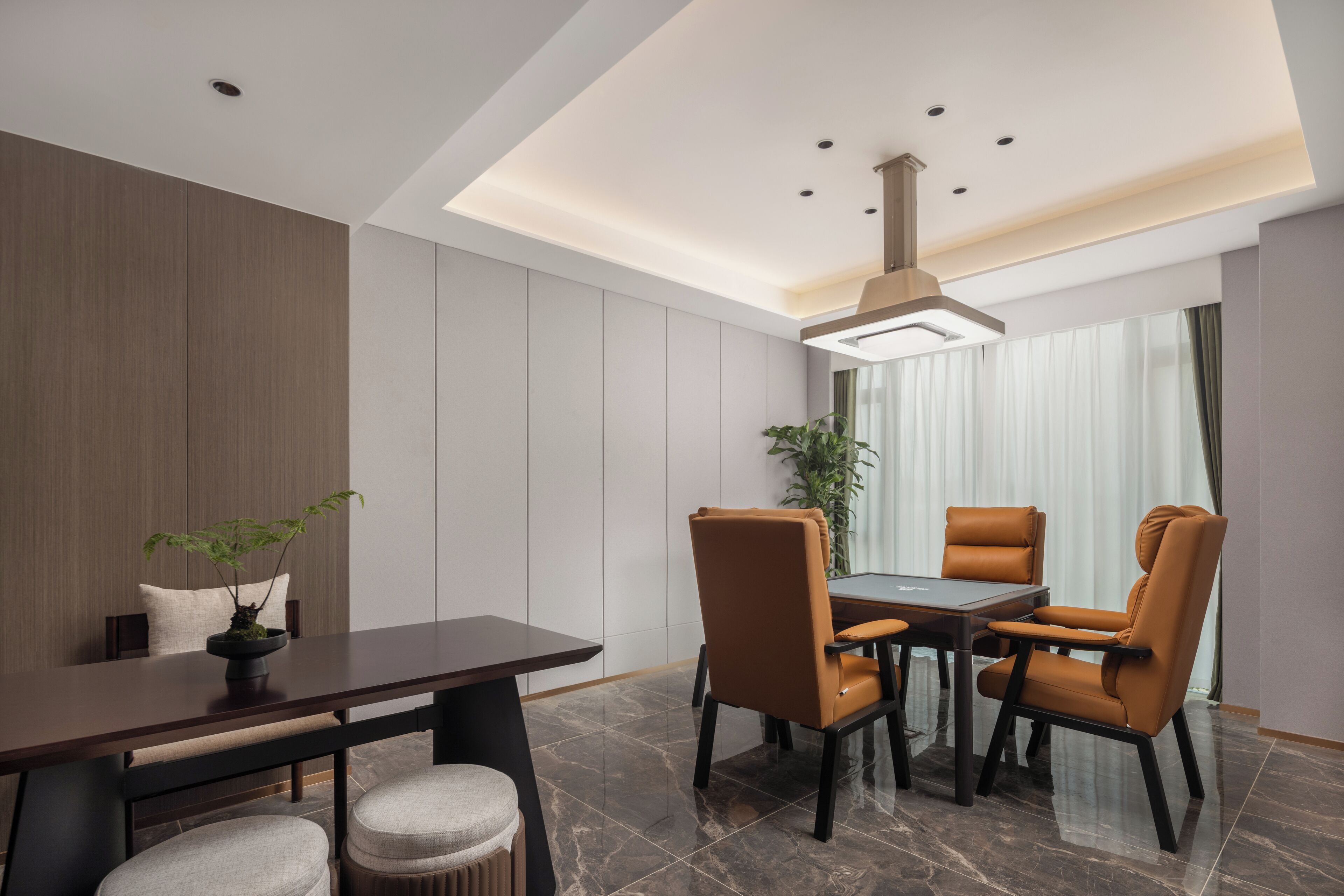 Un comedor moderno con una mesa de madera oscura, cuatro sillas de cuero marrón, una planta en maceta y una lámpara colgante.