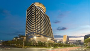 A modern hotel with a curved facade, multiple floors, and a prominent entrance. - Wyndham Grand Shenzhen Guangming (Shenzhen)
