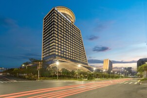 A modern hotel with a curved facade, multiple floors, and a prominent entrance.