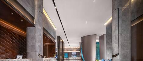 A modern lobby with marble reception desks, high ceilings, and a sleek, curved design.