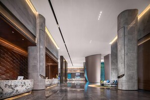 A modern lobby with marble reception desks, high ceilings, and a sleek, curved design.