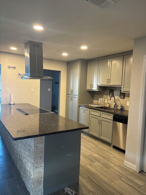 A modern kitchen with a granite countertop, stainless steel appliances, and light-colored cabinetry. - Ultimate Game Day Stay, 3BR House +Pool Near AT&T Stadium but far from the noise (Arlington)