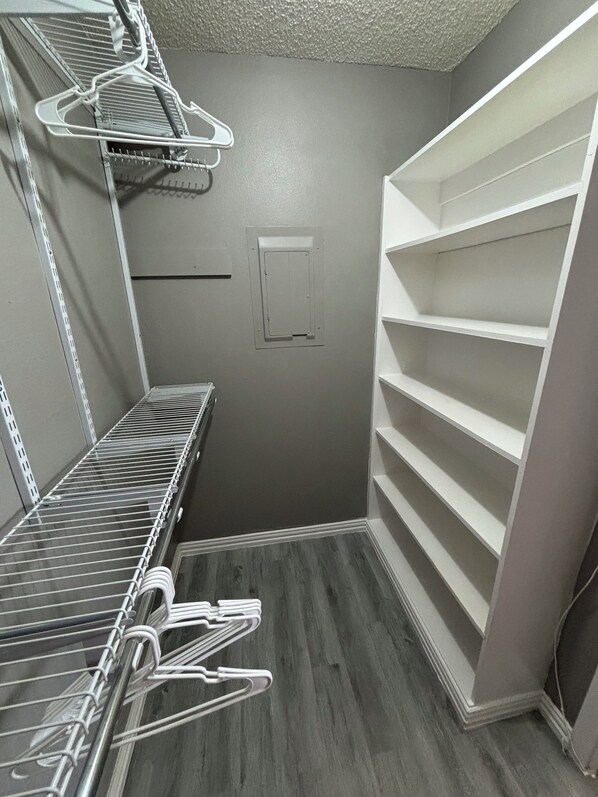 Un vestidor con repisas metálicas, un tendedero de metal y una puerta blanca con manija.