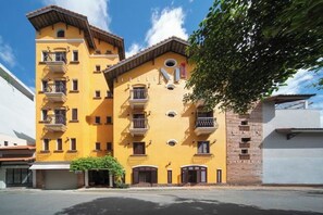 A yellow multi-story building with balconies and a brick facade.