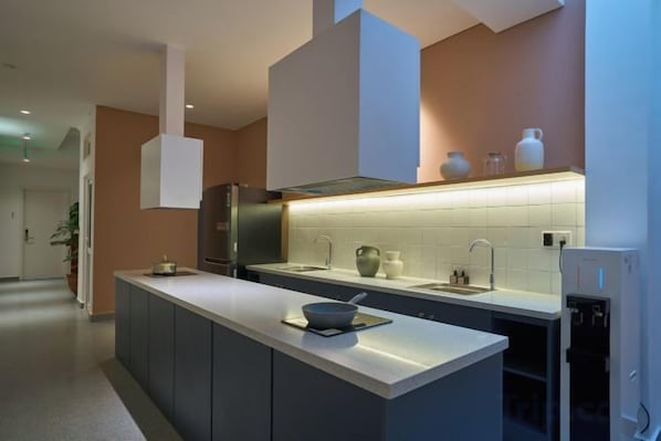 A modern kitchen with a central island, a built-in oven, and a stainless steel range hood.