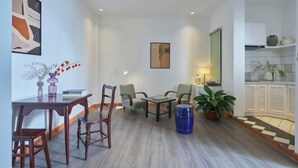 A modern living room with a dining area, featuring a coffee table, chairs, and a blue barrel. - Express by M Village Cach Mang Thang 8, a brand of Modern Village Lifestyle (Ho Chi Minh City)