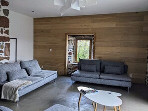 Una sala de estar moderna con dos sofás grises, una mesa de centro blanca y una pared de piedra.