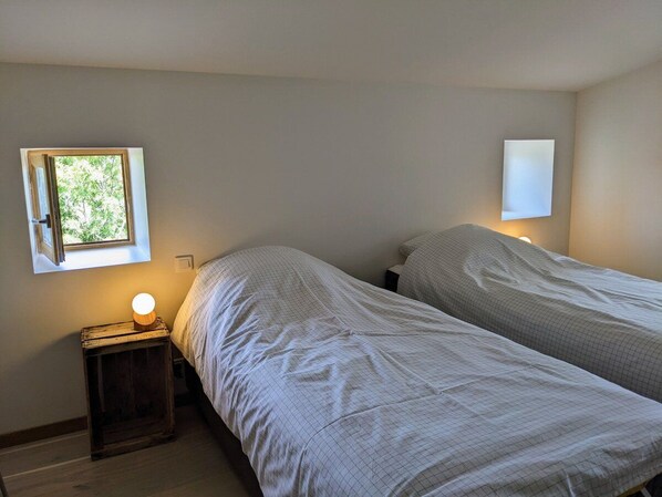Un dormitorio con dos camas, una ventana y una lámpara de noche.