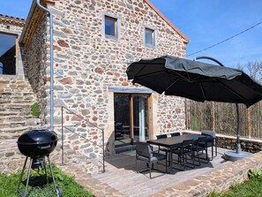 Una casa de piedra con una parrilla y zona de estar al aire libre.