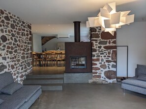 Una sala de estar moderna con una pared de piedra, una chimenea y un comedor al fondo.
