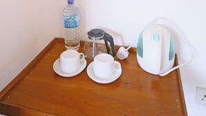 A small wooden table with a water bottle, a glass carafe, two white cups, and a white electric kettle. - Ella Floating View (Ella)