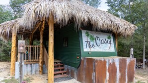 A rustic wooden structure with a thatched roof and a sign reading "The Oasis." - The Oasis - a shabby-chic, glamping escape to the wild side at Oak Meadow Ranch (Valley View)
