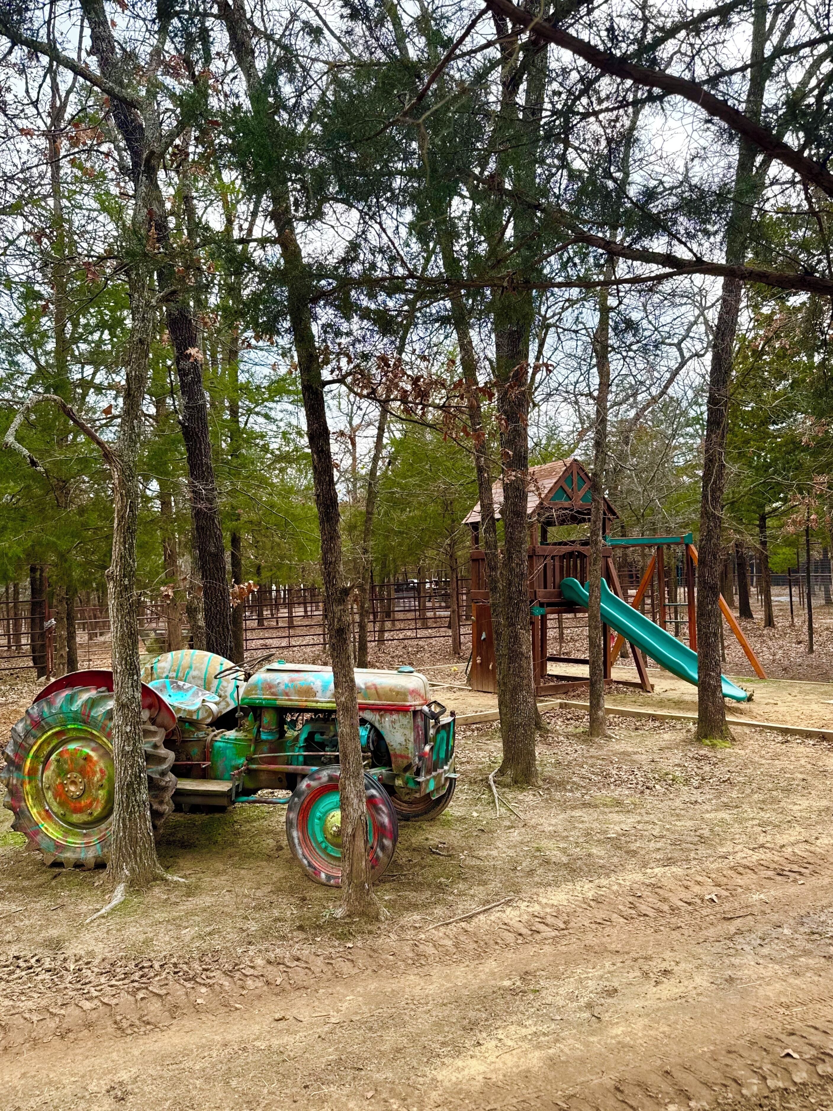 A playground with a slide and a playhouse, surrounded by trees.