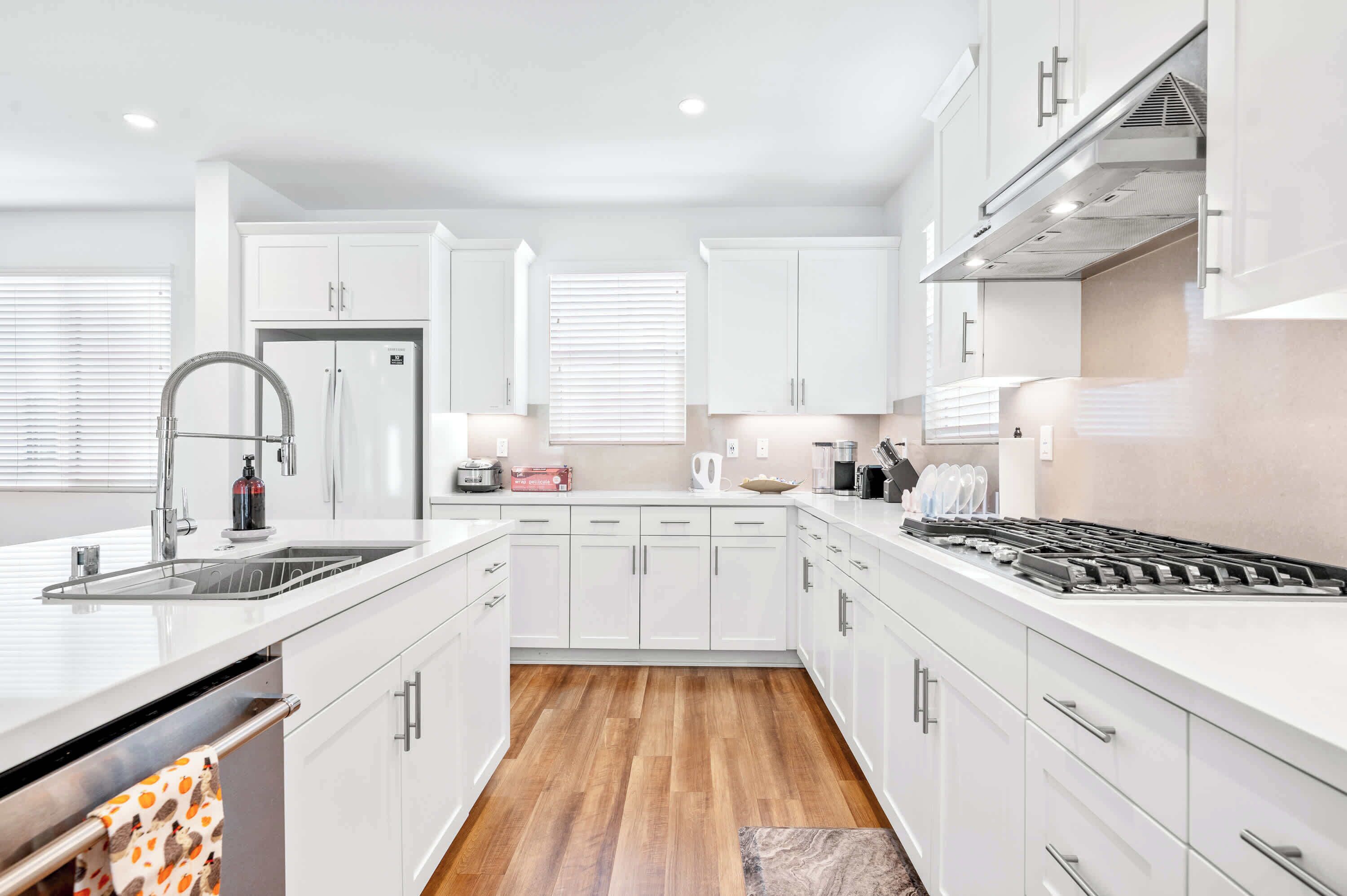 A modern kitchen with white cabinetry, a stainless steel sink, and a gas stove.