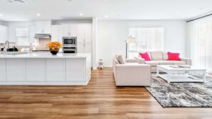 A modern kitchen with white cabinets, a central island, and a microwave. - Central Location Cozy Private Bedroom w Bathroom (Irvine)