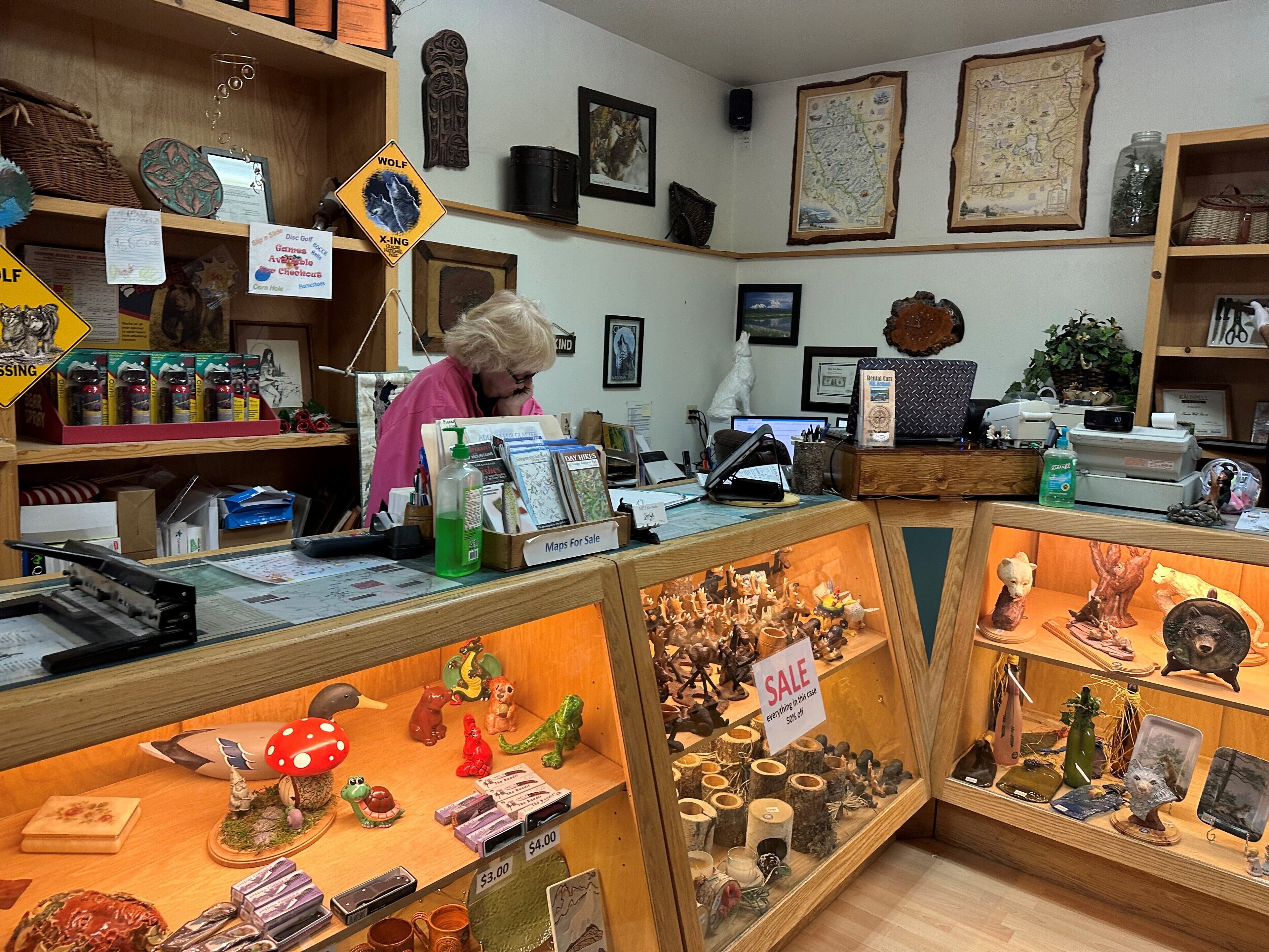 A small shop with various items for sale, including maps, figurines, and a sign indicating a sale.